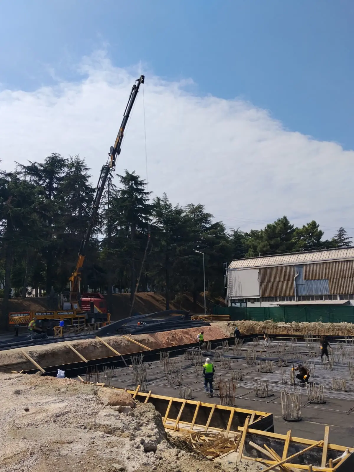 Temel kazısı kenarında mobil vinç; kalıp ve donatı hazırlığı