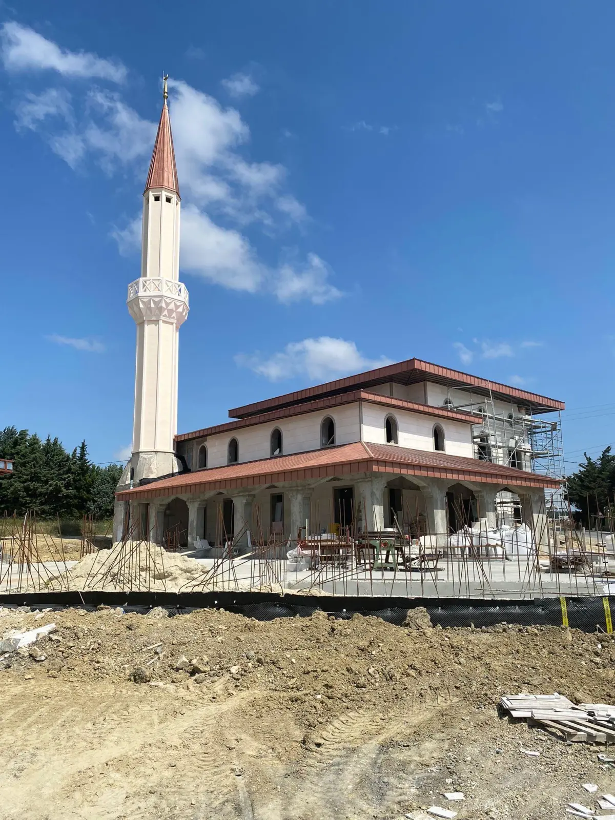 İnşaat aşamasında tamamlanmış minare; iki kademeli kiremit çatı ve avlu tesviyesi süren cami