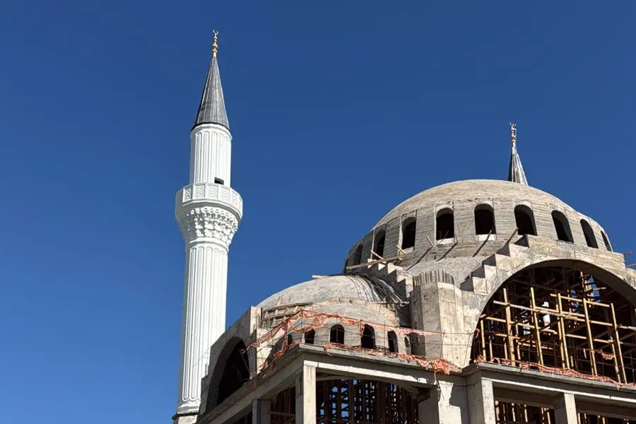 Sokak kotundan cami ve minare — kaba yapı ve ahşap kalıp iskelesi