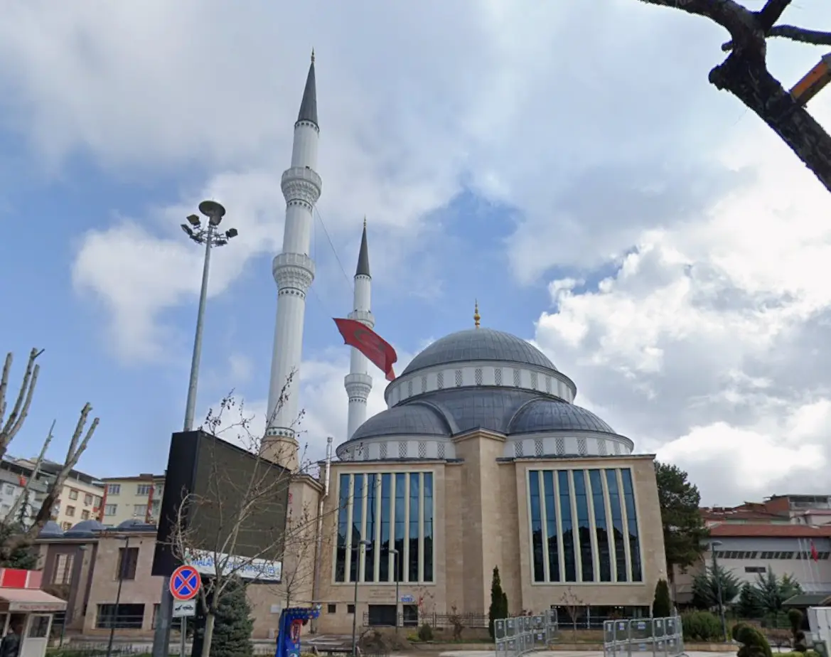 Sokaktan üç çeyrek görünüm — yüksek kemerli pencereler, ana kubbe ve çift minare