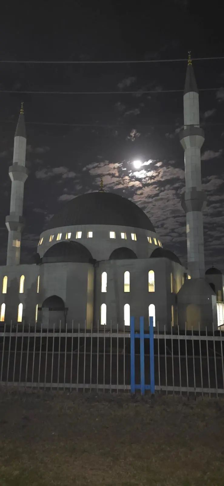 Gün batımında Melbourne Camii — aydınlatılmış cephe, iki minare ve hilal