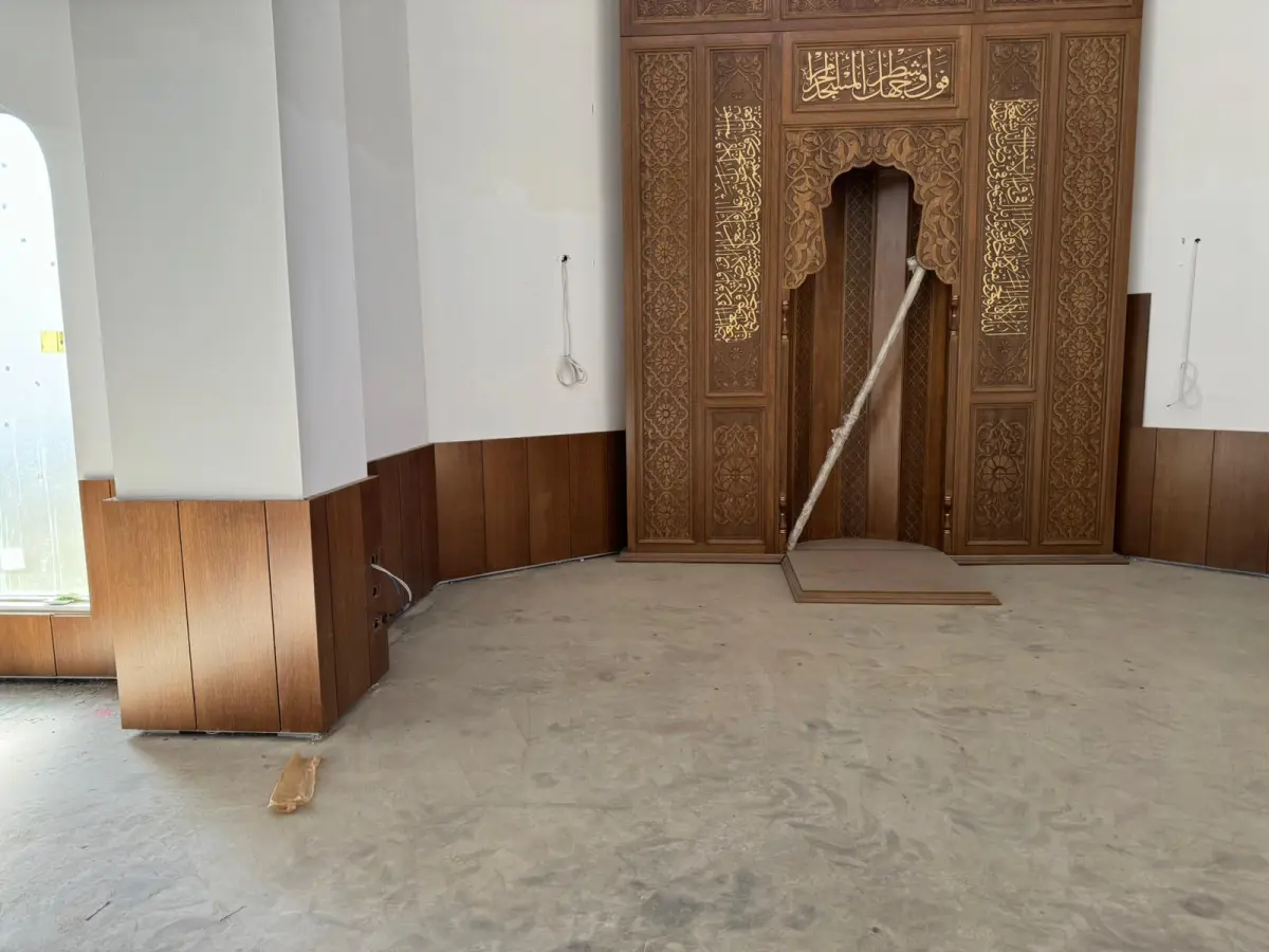 Mihrap yakın plan — oyma ahşap yüzey, hat kuşağı ve ahşap lambri