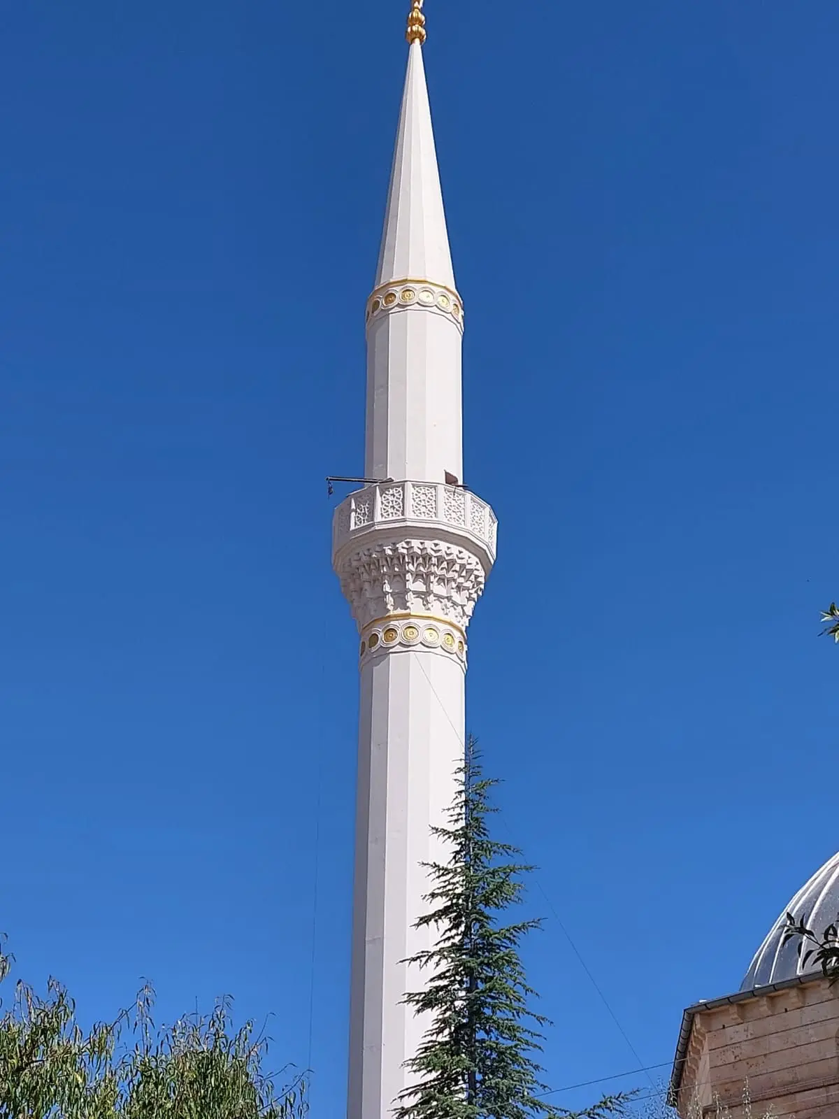 Minarenin mukarnaslı şerefesi ve altın bilezik detayı — yakın plan