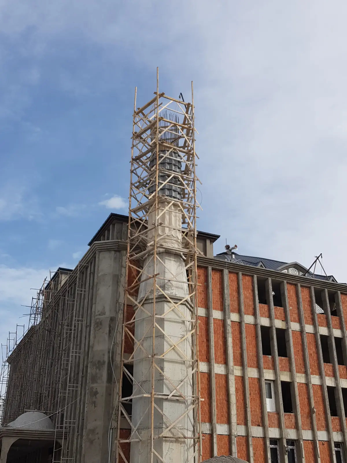 Minare inşaatının genel görünümü; iskele kurulu gövde ve arkada cami kaba yapısı