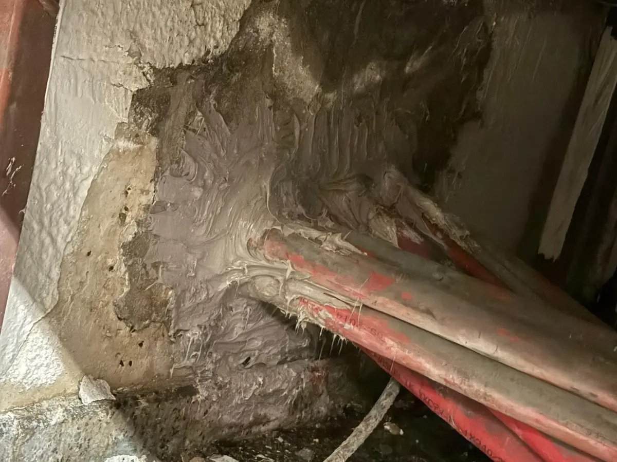 Perdeden geçen kırmızı OG kablo boruları, çimento esaslı harçla kapatılmış hâlde