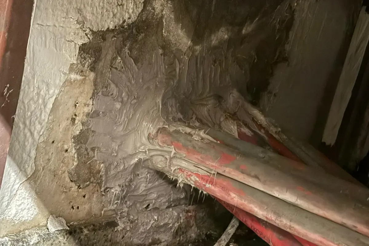 Perdeden geçen kırmızı OG kablo boruları, çimento esaslı harçla kapatılmış hâlde